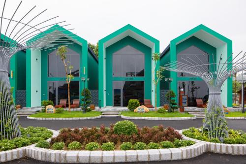 a green building with palm trees in front of it at Trân Châu Beach & Resort in Ba Ria