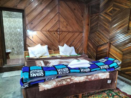 two beds in a room with wooden walls at kailwood Guest House in McLeod Ganj