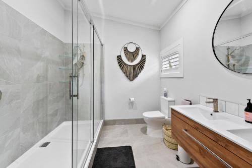 a bathroom with a shower and a sink and a toilet at The Olde Store - Hunua Holiday Home in Hunua