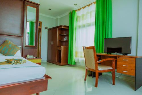 a bedroom with a bed and a desk with a television at Greenlight Hotel in Dar es Salaam