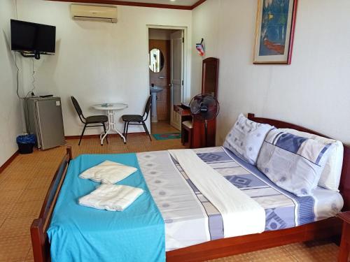 a bedroom with a bed and a table with chairs at MB's Garden Inn in Mactan