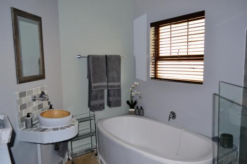a bathroom with a tub and a sink and a mirror at Cherry Grove 2 in Dullstroom