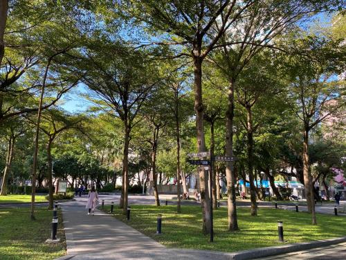 a park with trees and a person walking down a sidewalk at CHECK inn Taipei Main Station in Taipei