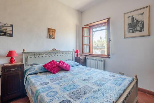 a bedroom with a bed with pink pillows on it at Chiantishire Lovely Cottage with Garden & Parking! in Castelnuovo Berardenga