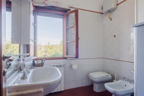 a bathroom with a sink and a toilet and a window at Chiantishire Lovely Cottage with Garden & Parking! in Castelnuovo Berardenga