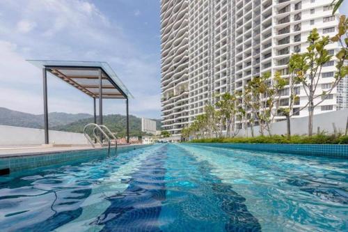 ein Schwimmbad vor zwei hohen Gebäuden in der Unterkunft Deluxe Seaview Suite Twin Bed by The Only Bnb in Tanjong Tokong