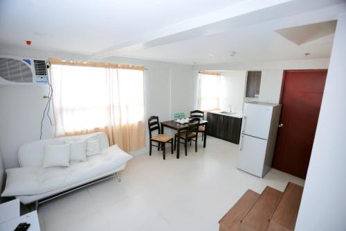 a living room with a white couch and a kitchen at Gilmore Tower Suites By SMS Hospitality in Quezon City