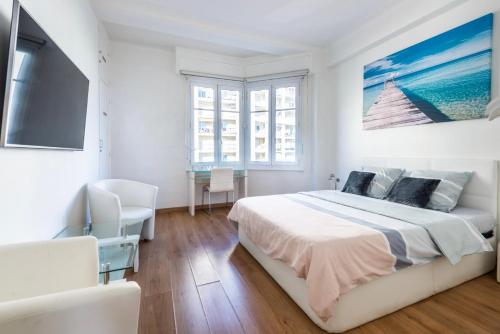 a white bedroom with a large bed and a flat screen tv at SEA FRONT - Panoramic view with Terraсe - 2BR in Nice