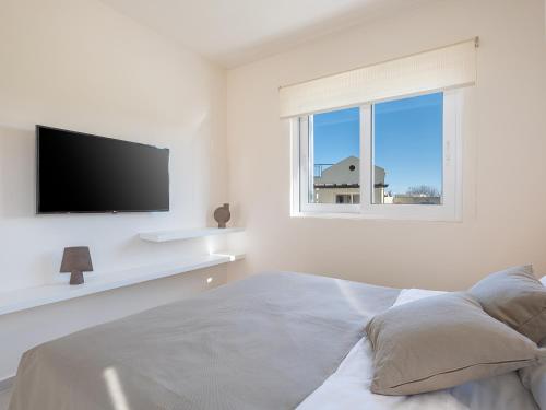 a white bedroom with a flat screen tv and a bed at Calmaliving Seaside apartments with pool in Gerani Chanion
