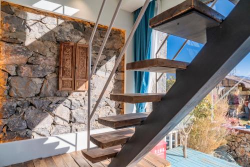 a staircase in a house with a stone wall at 玉龙白沙普宿客栈 in Lijiang