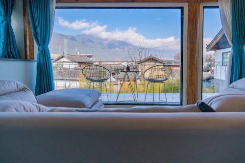 a bedroom with a large window with a view at 玉龙白沙普宿客栈 in Lijiang