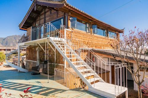 a house with a staircase on the side of it at 玉龙白沙普宿客栈 in Lijiang