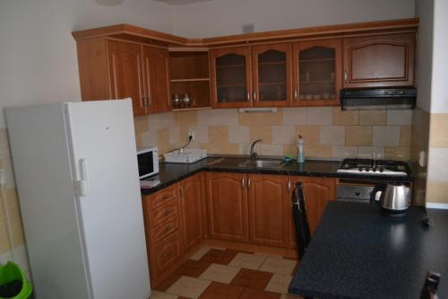 a kitchen with wooden cabinets and a white refrigerator at Penzion Abahouse in Liptovský Mikuláš