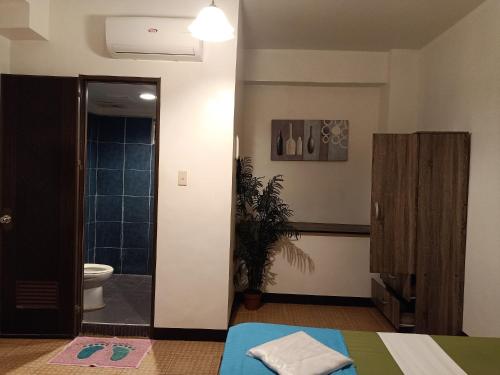 a bathroom with a bed and a toilet in a room at MB's Garden Inn in Mactan