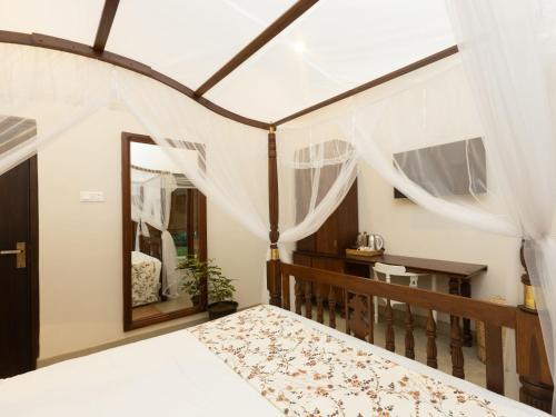 a bedroom with a bed with curtains and a mirror at Edgar Mansion Kandy in Kandy