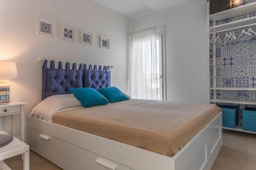 1 dormitorio con 1 cama grande con almohadas azules en Virgilio - Con servizio spiaggia - Narramondo Villas, en Tortoreto Lido