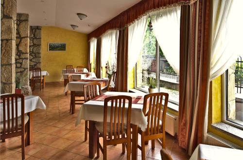a restaurant with tables and chairs and large windows at Bajka in Krynica Zdrój