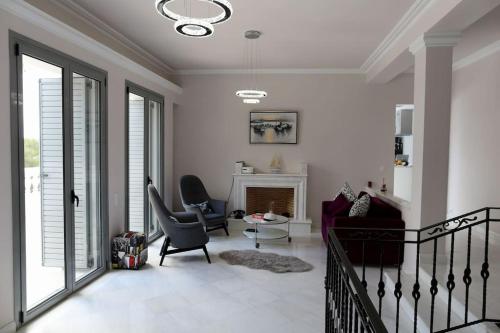 a living room with a couch and chairs and a fireplace at The White House Beach Villa in Rafina