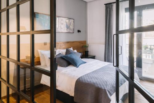 a bedroom with a bed with white sheets and blue pillows at The 4 Travellers Thessaloniki in Thessaloniki