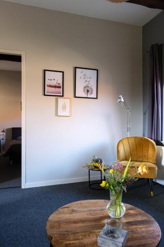 a room with a table and a chair and a vase of flowers at Hoeve de Binnenplaets Schimmert in Schimmert
