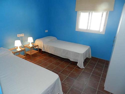 a blue room with two beds and a window at DADA CAÑOS in Los Caños de Meca
