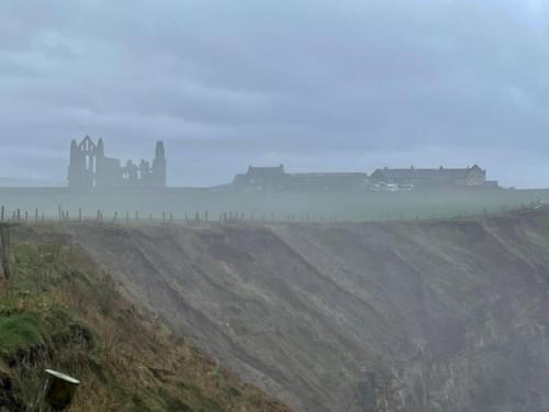 a foggy field with a castle in the distance at Robin Hood's Bay Coastguard's Cottage with a View in Robin Hood's Bay