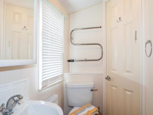 Baño blanco con aseo y lavamanos en Mountain View Lodge 2, en Holyhead