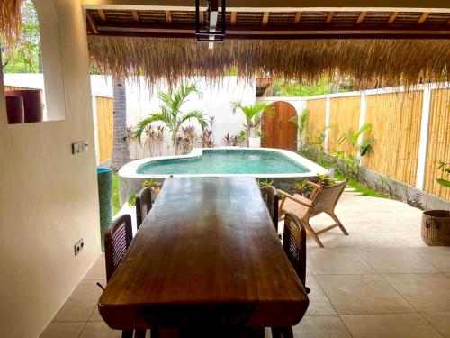 a wooden table with chairs and a swimming pool at La Villa Loca in Gili Air