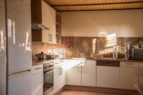 a kitchen with white cabinets and stainless steel appliances at Pension Am historischen Kalkwerk in Bahretal