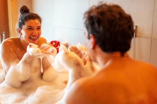 a man in a bath tub with a woman in a mirror at Madlhof in Himmelreich