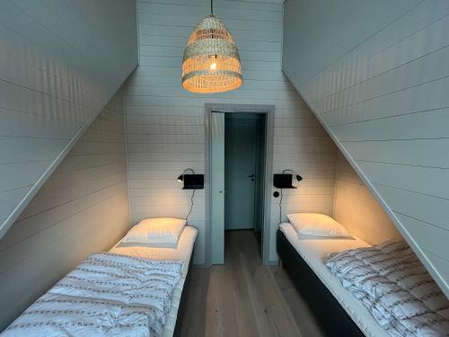two beds in a attic room with a chandelier at Kåvan Townhouse Funäsdalen in Funäsdalen