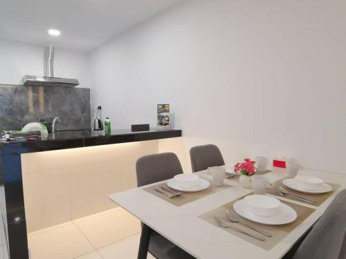 a kitchen with a table with chairs and plates on it at Sibu Q1 Homestay -3 Rooms 4 Beds in Sibu