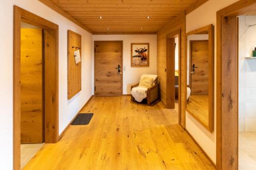 a hallway with wooden floors and a chair in a room at Madlhof in Himmelreich