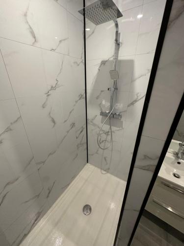 La salle de bains est pourvue d'une douche et de murs en marbre blanc. dans l'établissement Appartement meublé proche du futuroscope, à Poitiers