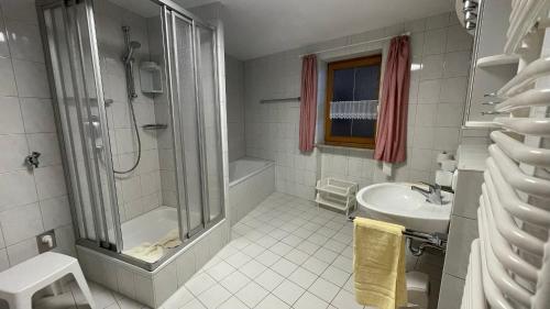 a white bathroom with a shower and a sink at Ferienwohnung Pauliner in Oberstdorf