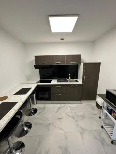 La cuisine est équipée de placards bruns et d'un évier. dans l'établissement Appartement meublé proche du futuroscope, à Poitiers