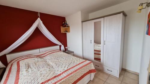 um quarto com uma cama e uma parede vermelha em Ferienwohnng Sander em Halsbrücke