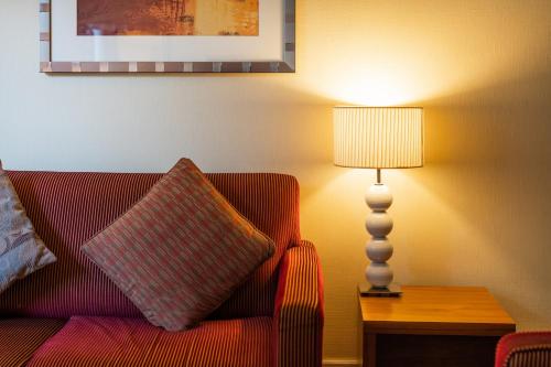 a living room with a red couch and a lamp at Orida Maidstone in Maidstone