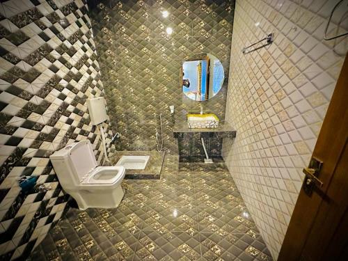 Un baño con inodoro, lavabo y espejo. en The Signature Hotel Multan, en Multán