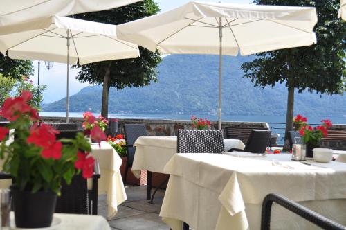 a restaurant with tables with flowers and umbrellas at Hotel Il Portico by LVG Hotel Collection in Cannobio