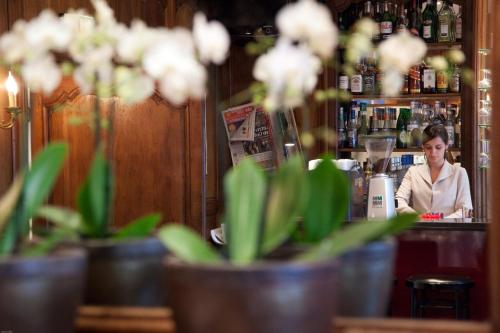 a woman behind the counter of a bar with white flowers at Hotel München Palace in Munich
