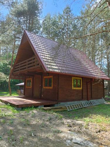 una pequeña casa de madera con porche en un bosque en Dom Sosnowy, en Szczytno