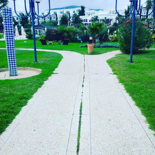 a walkway in a park with grass and blue poles at Marina Smir Hotel & Spa in M'diq