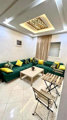 a living room with a green couch and a table at Tanagra Mall appartement de Luxe a côté de la Gare TGV in Kenitra