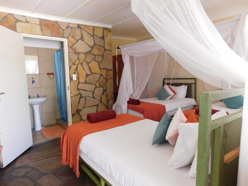 1 dormitorio con 2 camas y baño con lavamanos en Tsumkwe Country Lodge, en Tsumkwe