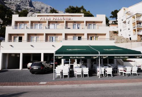 a building with tables and chairs in a parking lot at Villa Palloma in Baška Voda