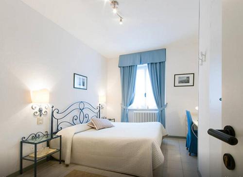 a white bedroom with a bed and a window at Miralago B&B and Apartments in Bellagio