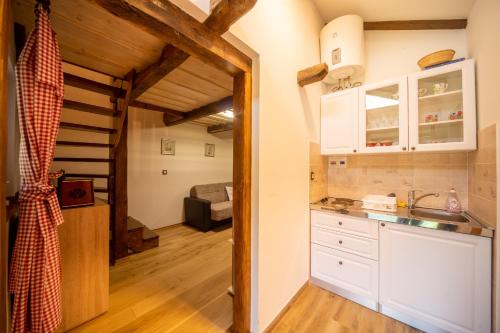 a kitchen with white cabinets and a living room at VAL HILLS Rural Holiday House in Gaj Vrbovečki
