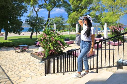a woman standing on a fence talking on a cell phone at Ilirija Resort Hotel Adriatic in Biograd na Moru