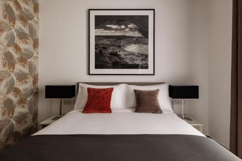 a bedroom with a white bed with red pillows at Urban Isle in Il-Gżira
